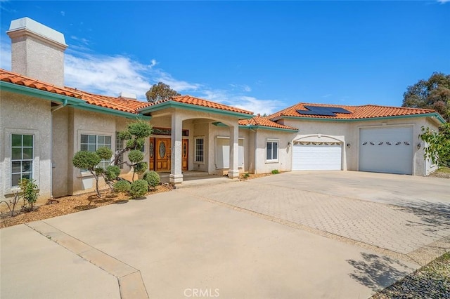 mediterranean / spanish-style house featuring solar panels, concrete driveway, a porch, and stucco siding