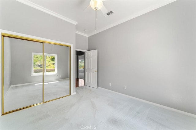 unfurnished bedroom with crown molding, a closet, ceiling fan, carpet, and baseboards