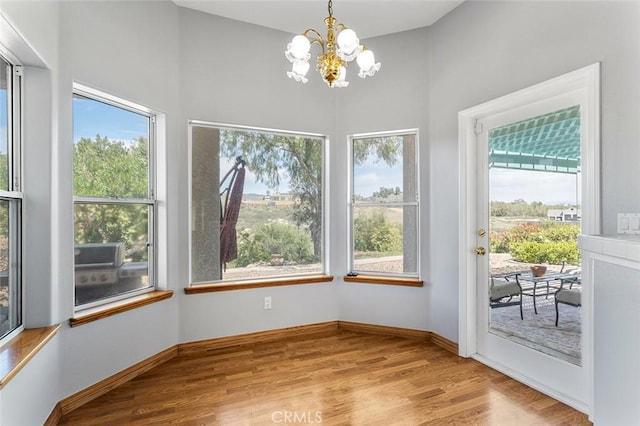 unfurnished dining area featuring a towering ceiling, baseboards, wood finished floors, and a notable chandelier