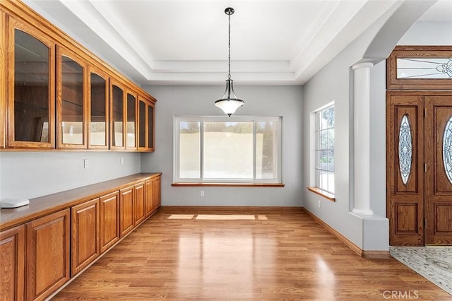 entryway with light wood finished floors, decorative columns, and baseboards