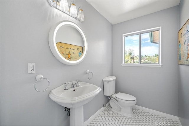 bathroom featuring baseboards, toilet, and a sink