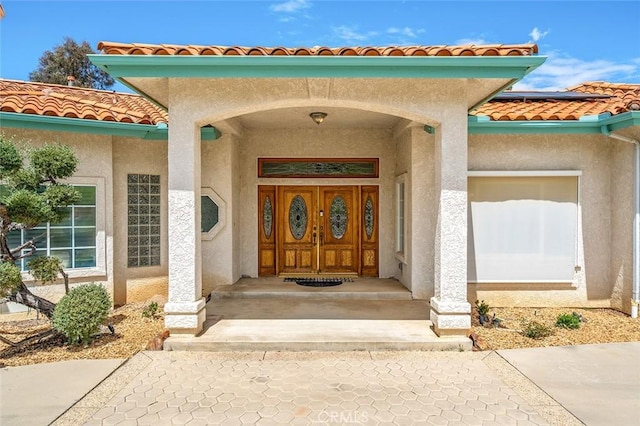 doorway to property featuring solar panels, a tile roof, and stucco siding
