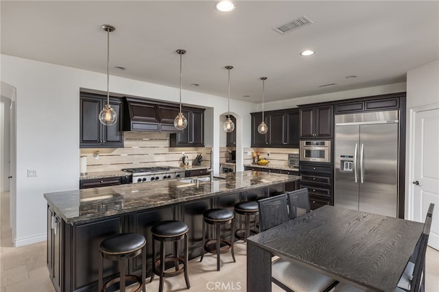 29311 Paseo Palmar, San Juan Capistrano, CA 92675 - kitchen featuring stainless steel appliances, backsplash, a spacious island, dark stone counters, and pendant lighting