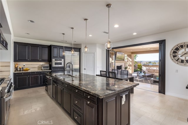 29311 Paseo Palmar, San Juan Capistrano, CA 92675 - kitchen featuring a sink, stainless steel appliances, a center island with sink, dark stone countertops, and decorative light fixtures