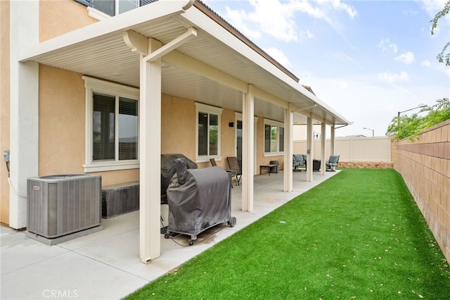 rear view of house with a patio area, a fenced backyard, a yard, cooling unit, and stucco siding