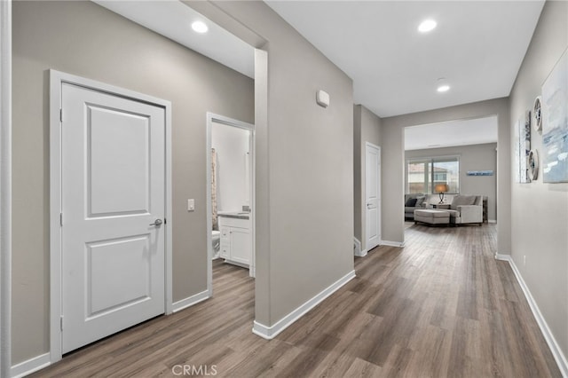 hall featuring baseboards, wood finished floors, and recessed lighting