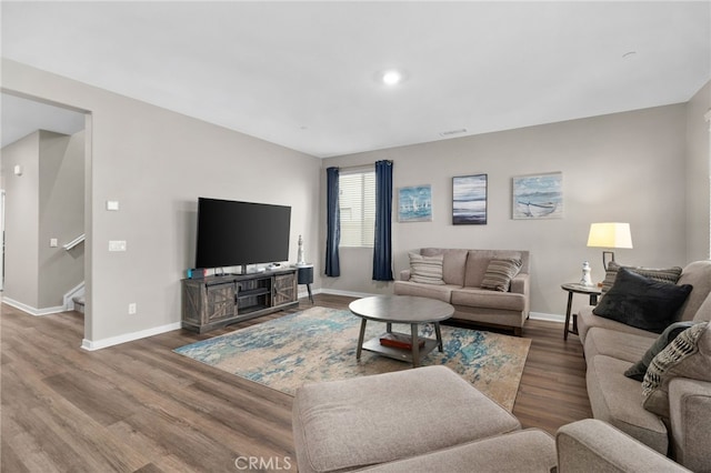 living room with stairway, baseboards, wood finished floors, and visible vents