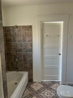 586 W 1st St, San Pedro, CA 90731 - full bath featuring toilet, shower / bath combination, and tile walls