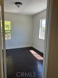 586 W 1st St, San Pedro, CA 90731 - empty room featuring dark wood-type flooring, plenty of natural light, and baseboards