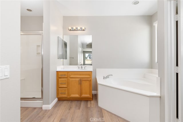 bathroom featuring vanity, wood finished floors, a bath, and a stall shower