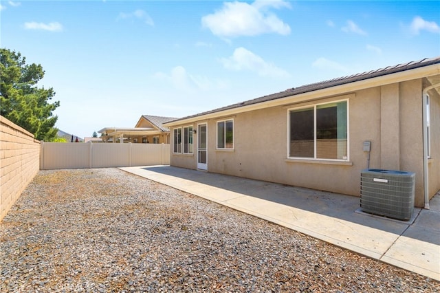 rear view of house featuring central air condition unit, stucco siding, a fenced backyard, and a patio area