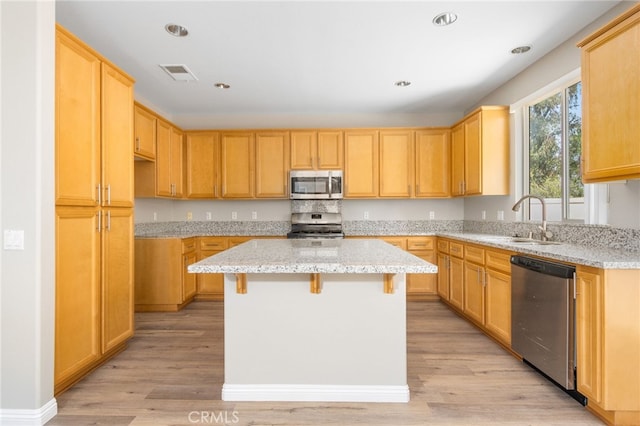 kitchen featuring stainless steel appliances, light stone countertops, visible vents, and a sink