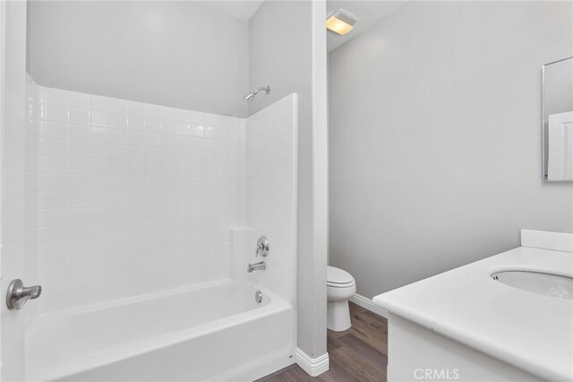 bathroom featuring vanity, wood finished floors, toilet, baseboards, and washtub / shower combination
