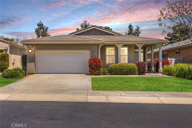 view of front facade featuring a garage, stucco siding, a tiled roof, concrete driveway, and a yard