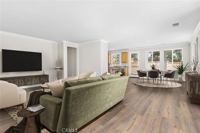 living room with visible vents, crown molding, and wood finished floors