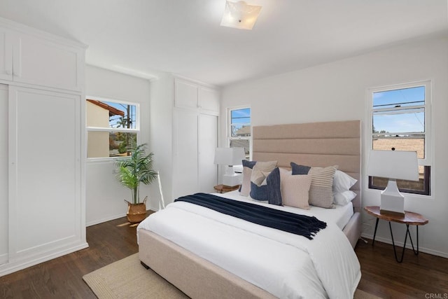 bedroom with dark wood finished floors and baseboards