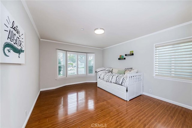 bedroom with baseboards, crown molding, and wood finished floors