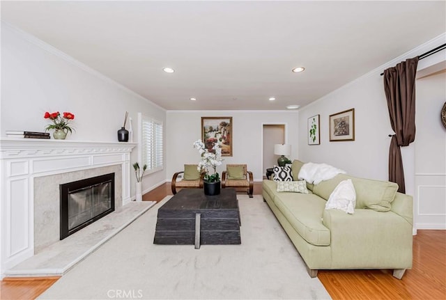 living room featuring a fireplace, ornamental molding, wood finished floors, and recessed lighting