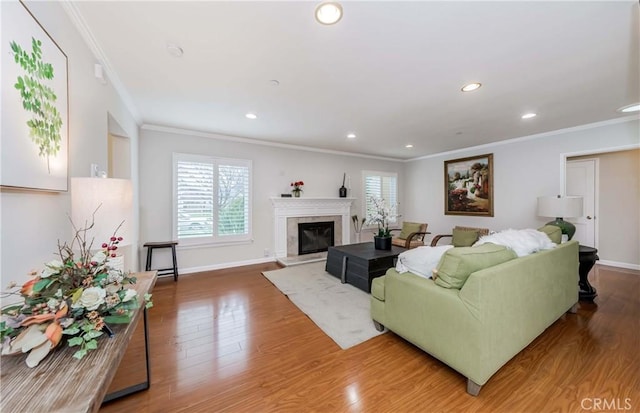 living area with a fireplace, wood finished floors, baseboards, and ornamental molding