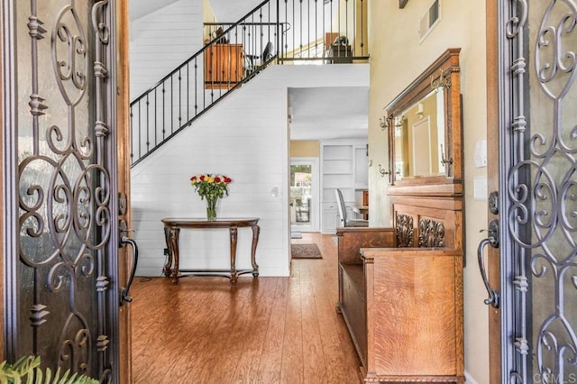 foyer entrance featuring stairway, a high ceiling, wood finished floors, and visible vents