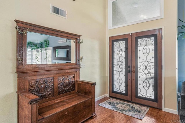 foyer entrance with visible vents, baseboards, wood finished floors, and french doors