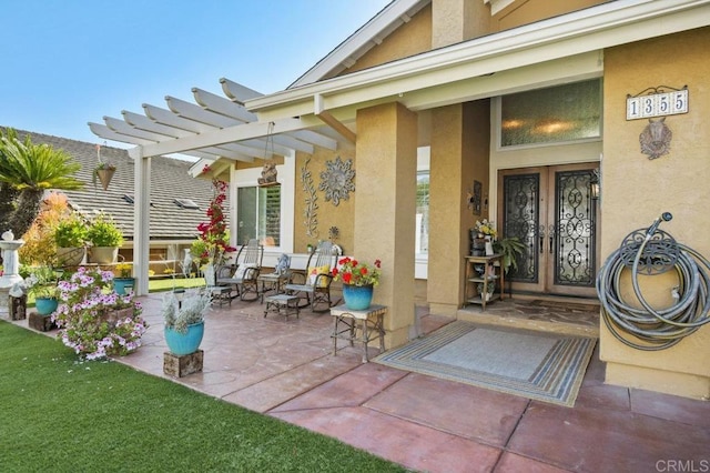 property entrance with french doors, a pergola, stucco siding, and a patio area