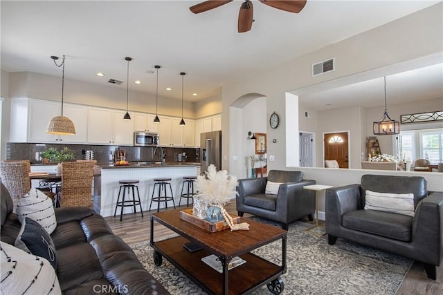 living area featuring a ceiling fan, visible vents, and wood finished floors