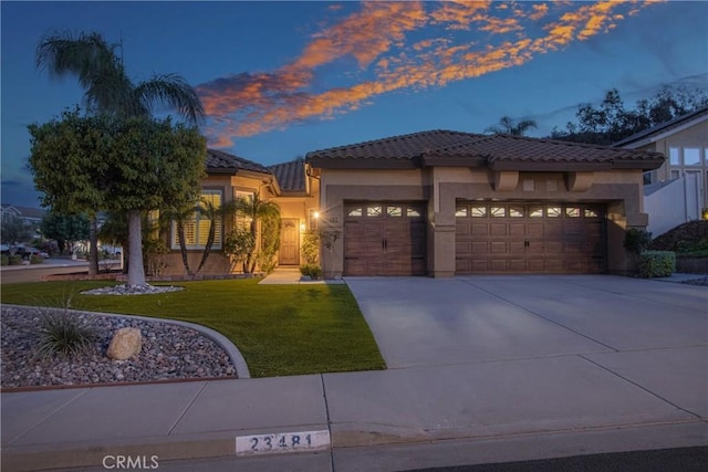 view of front of home with driveway, a tile roof, stucco siding, a front lawn, and a garage