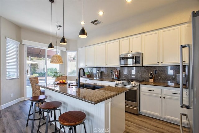kitchen with white cabinets, a sink, visible vents, stainless steel appliances, and backsplash