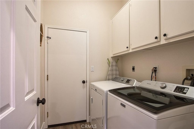 laundry area with separate washer and dryer, cabinet space, and wood finished floors