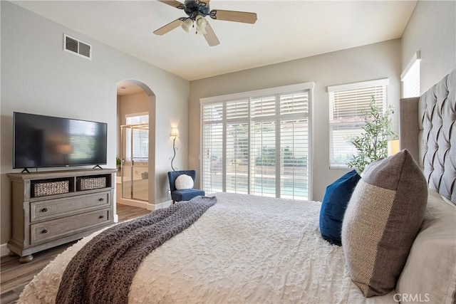 bedroom featuring arched walkways, visible vents, wood finished floors, and baseboards