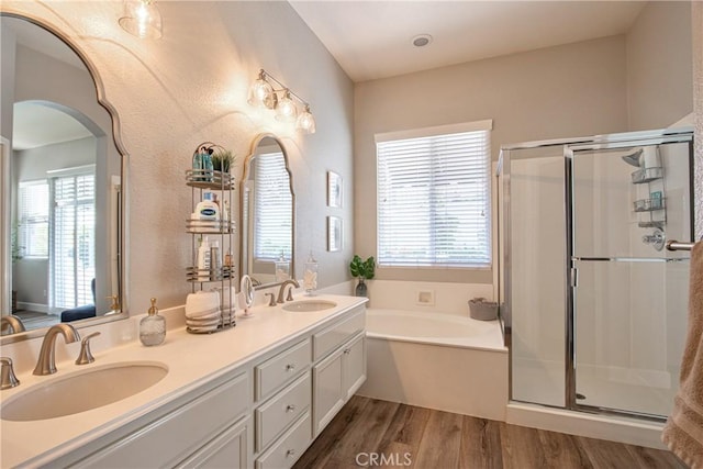 bathroom with wood finished floors, a bath, a stall shower, and a sink