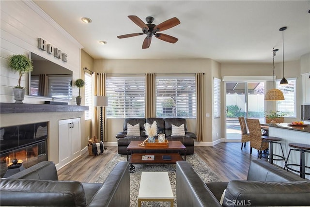 living room with recessed lighting, wood finished floors, a glass covered fireplace, baseboards, and a ceiling fan