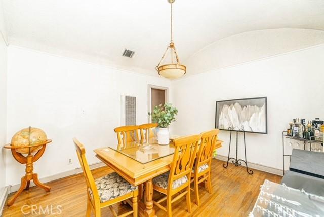 6114 Allston St, Los Angeles, CA 90022 - dining space featuring vaulted ceiling, visible vents, light wood finished floors, and baseboards
