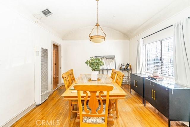 6114 Allston St, Los Angeles, CA 90022 - dining room with lofted ceiling, a heating unit, light wood-style floors, and visible vents