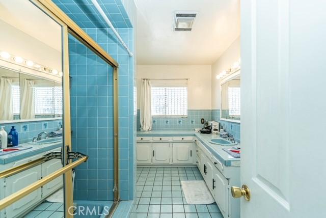 6114 Allston St, Los Angeles, CA 90022 - bathroom featuring tile patterned floors, tile walls, visible vents, decorative backsplash, and a shower stall