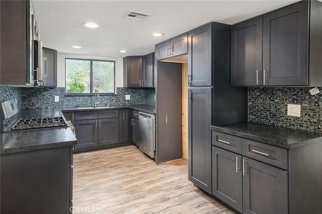 kitchen with dark countertops, stainless steel dishwasher, range with gas stovetop, and a sink