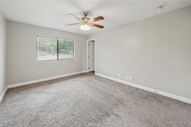 spare room with carpet floors, a ceiling fan, and baseboards