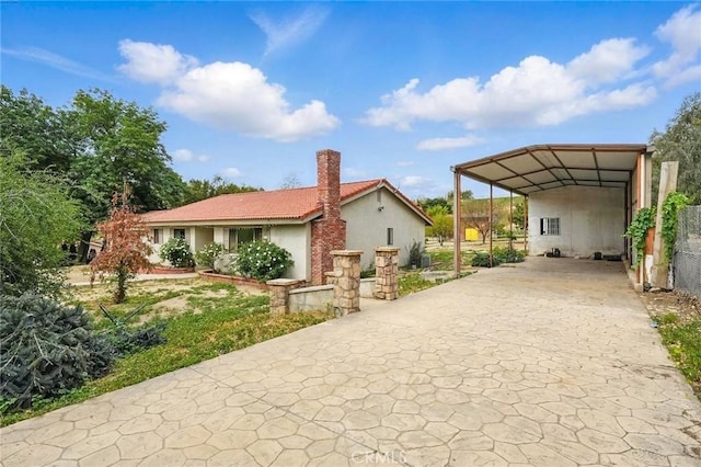 exterior space featuring stucco siding, driveway, a chimney, and a detached carport