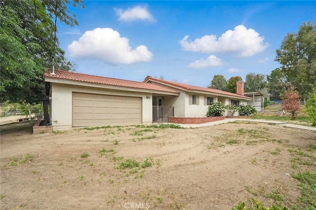 ranch-style home with stucco siding, dirt driveway, a tiled roof, and a garage