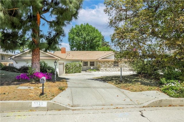 single story home featuring a chimney, stucco siding, driveway, and an attached garage