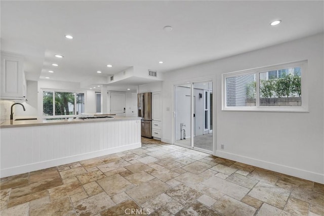 334 Tours Ln, Costa Mesa, CA 92627 - kitchen with white gas stovetop, stainless steel refrigerator with ice dispenser, a peninsula, stone tile flooring, and light countertops