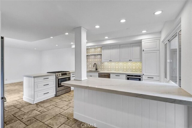 334 Tours Ln, Costa Mesa, CA 92627 - kitchen with stainless steel appliances, a peninsula, recessed lighting, white cabinetry, and decorative backsplash