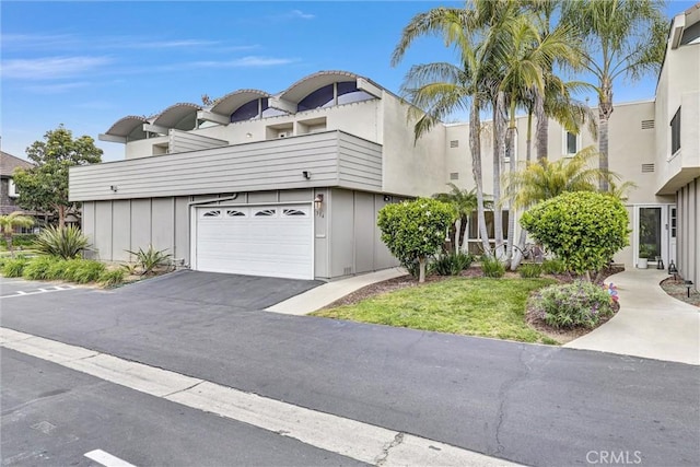 334 Tours Ln, Costa Mesa, CA 92627 - view of front facade with board and batten siding, asphalt driveway, and an attached garage