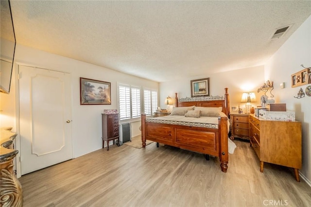 9527 Manzanita Dr, Rancho Cucamonga, CA 91737 - bedroom with radiator heating unit, a textured ceiling, visible vents, and light wood-style flooring