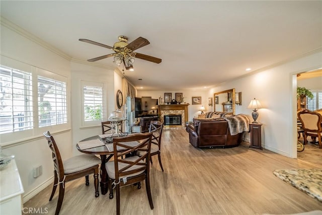 9527 Manzanita Dr, Rancho Cucamonga, CA 91737 - dining area featuring a glass covered fireplace, ceiling fan, light wood-style flooring, and ornamental molding