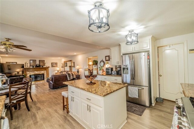 9527 Manzanita Dr, Rancho Cucamonga, CA 91737 - kitchen with white cabinets, light wood finished floors, stainless steel appliances, a center island, and a glass covered fireplace