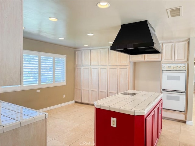 kitchen with double oven, light tile patterned floors, tile countertops, and ventilation hood
