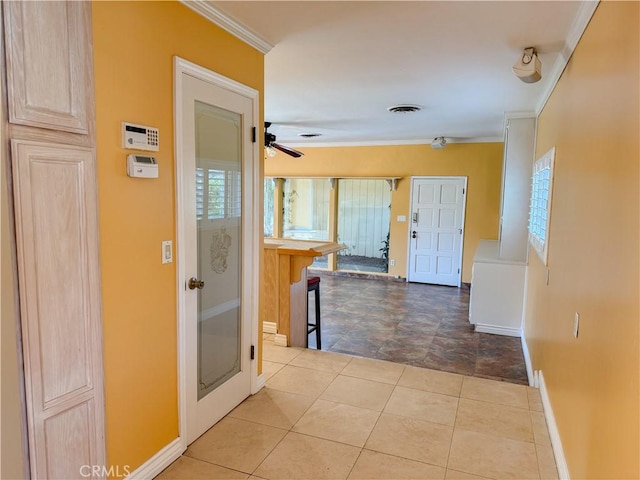 hall featuring visible vents, tile patterned floors, baseboards, and crown molding