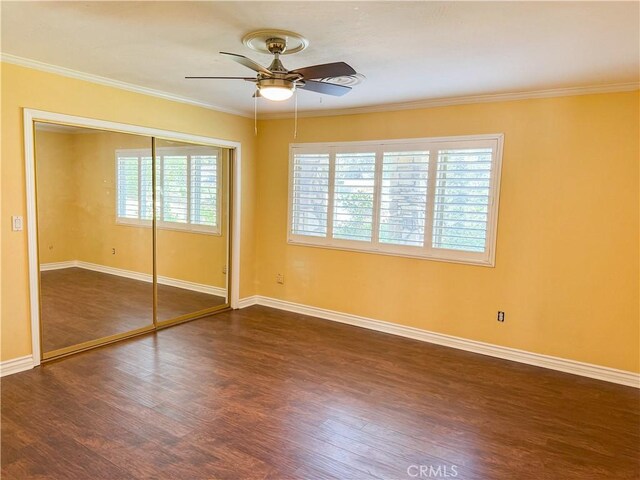 unfurnished bedroom featuring crown molding, a ceiling fan, a closet, dark wood finished floors, and baseboards